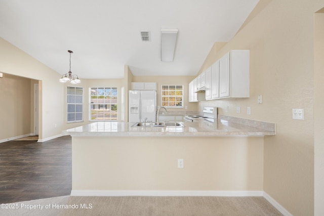 kitchen with white appliances, a peninsula, lofted ceiling, a sink, and light countertops