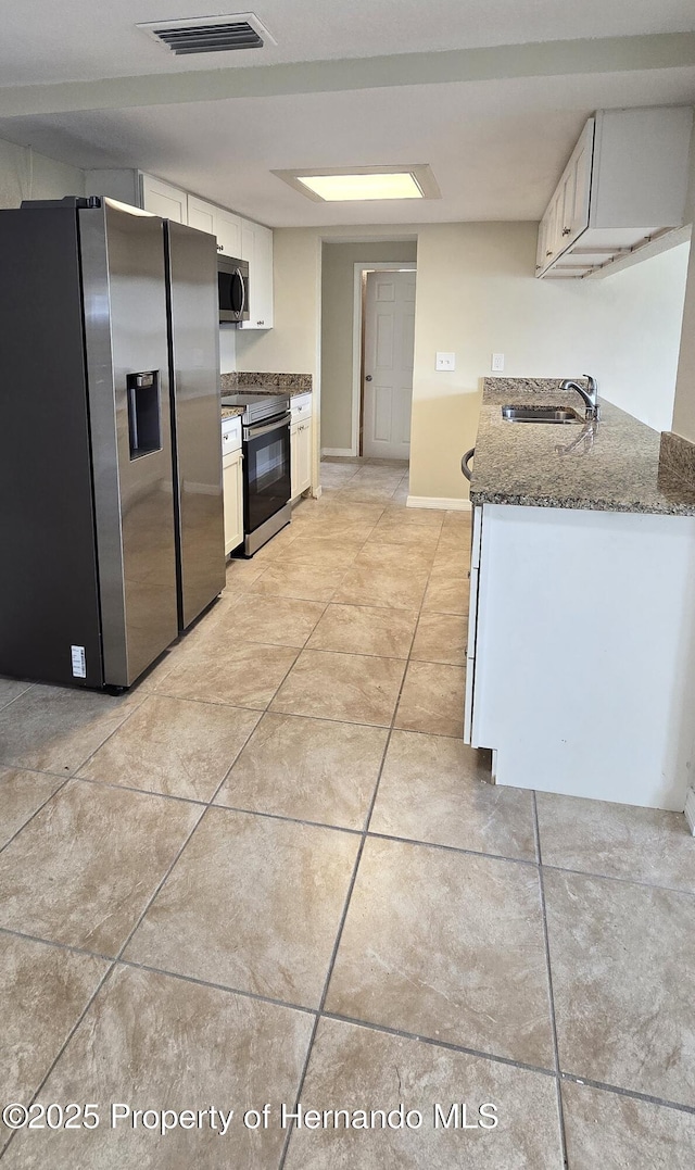16402 Killearn Ln, Spring Hill Pasco, FL 34610 - kitchen with stainless steel appliances, a sink, light tile patterned flooring, dark stone countertops, and white cabinetry