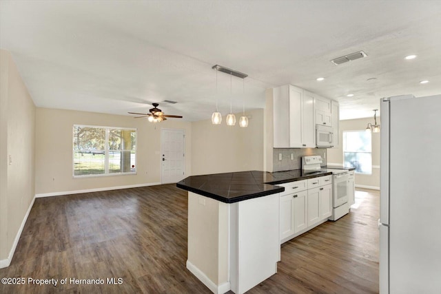 kitchen with visible vents, a peninsula, dark wood-style floors, white appliances, and white cabinetry