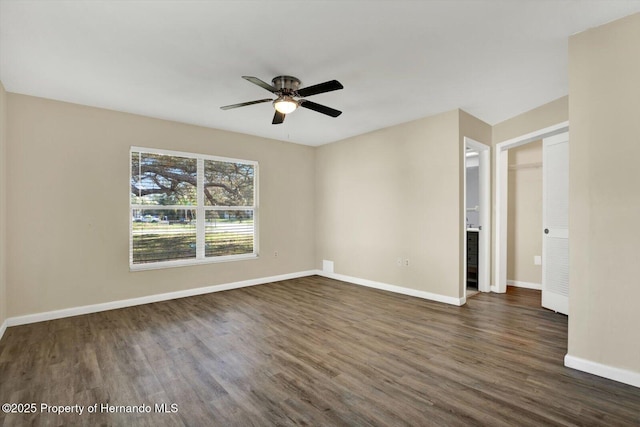 spare room featuring baseboards, dark wood-type flooring, and ceiling fan