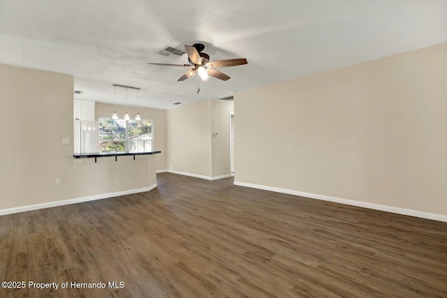 spare room featuring dark wood-style floors, visible vents, and baseboards