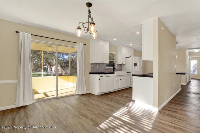 kitchen featuring backsplash, white appliances, white cabinetry, and light wood-type flooring