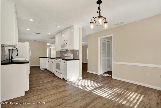 kitchen featuring visible vents, dark countertops, wood finished floors, white appliances, and decorative backsplash