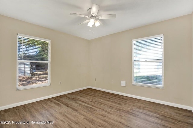 empty room with wood finished floors, baseboards, and ceiling fan