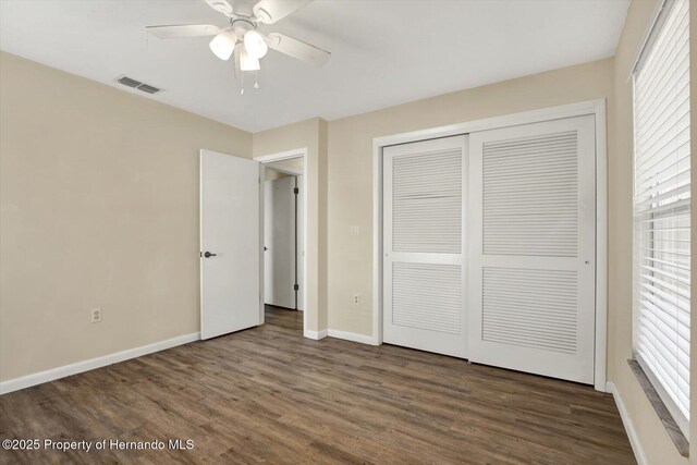 unfurnished bedroom featuring visible vents, baseboards, wood finished floors, a closet, and a ceiling fan