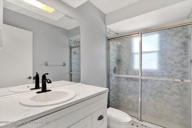 bathroom featuring a shower stall, vanity, and toilet