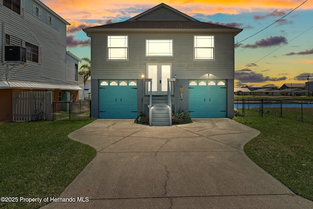 view of front facade featuring driveway, central AC, a front lawn, and fence