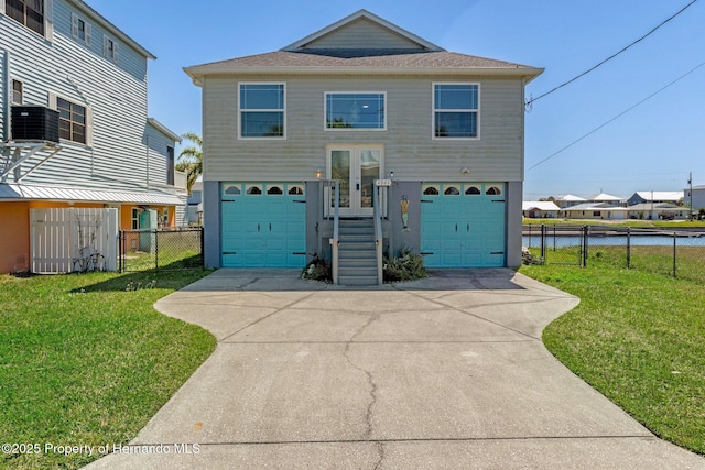 beach home with an attached garage, a front lawn, fence, french doors, and driveway