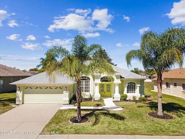 view of front of house featuring a front lawn, an attached garage, driveway, and stucco siding