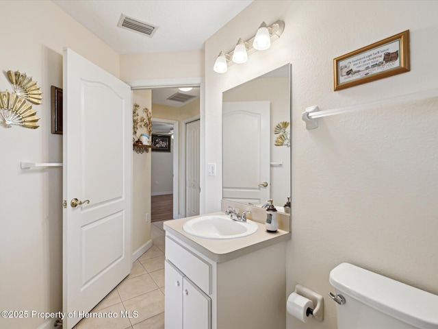 half bathroom with tile patterned floors, visible vents, toilet, and vanity