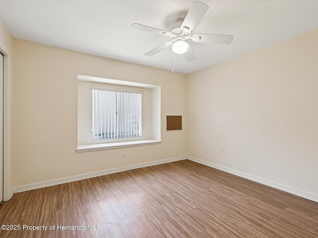 unfurnished room featuring ceiling fan, baseboards, and wood finished floors