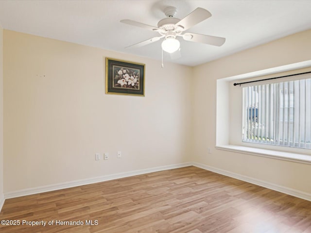 spare room featuring a ceiling fan, baseboards, and wood finished floors