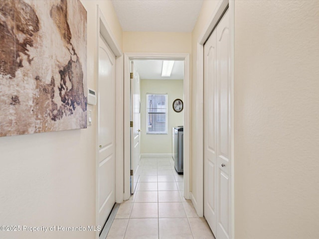 corridor with light tile patterned floors and washer / clothes dryer