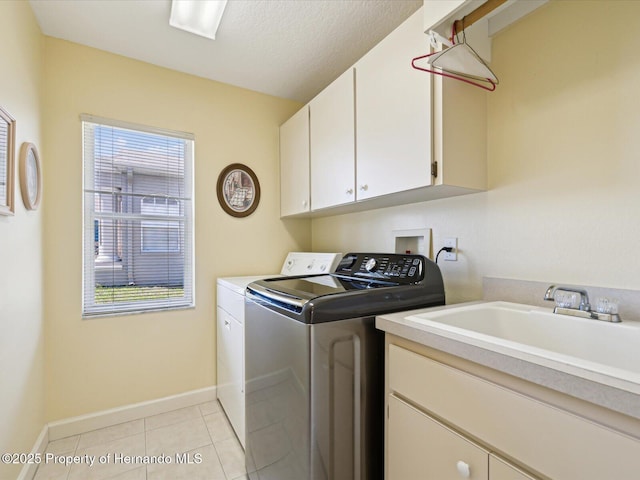 washroom featuring washing machine and clothes dryer, light tile patterned floors, a healthy amount of sunlight, and cabinet space