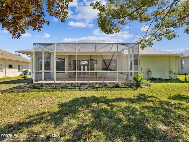 rear view of house featuring a yard, glass enclosure, a patio, and stucco siding