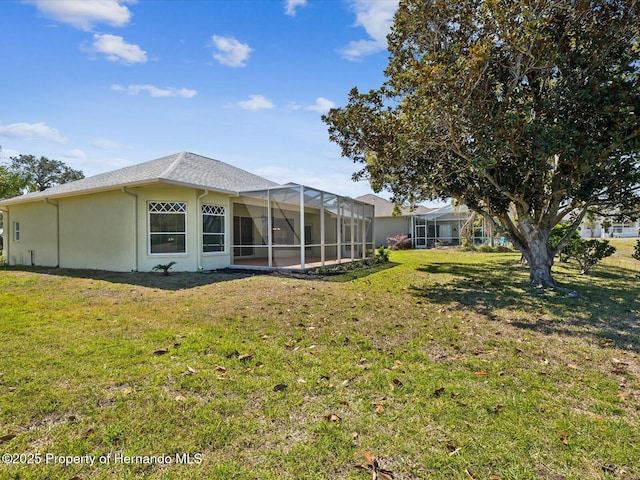 rear view of property featuring a lanai, stucco siding, and a lawn