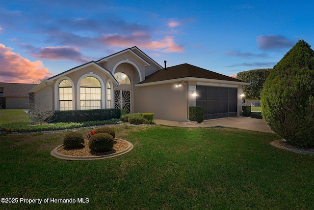 ranch-style house featuring stucco siding, a garage, concrete driveway, and a yard