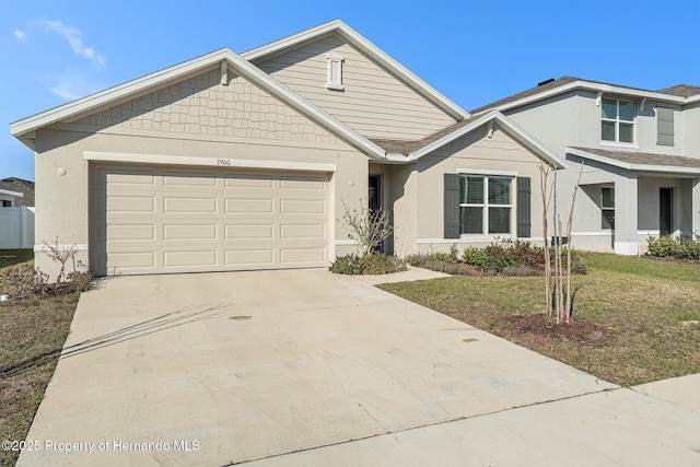 view of front of home with stucco siding, a front lawn, a garage, and driveway