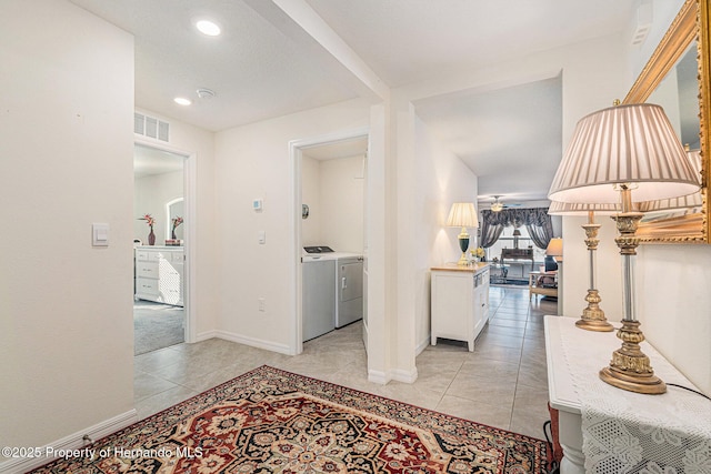 corridor with visible vents, baseboards, independent washer and dryer, and light tile patterned flooring