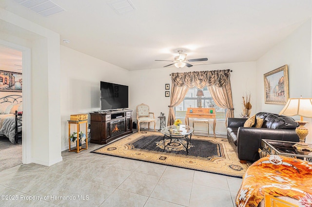 living area with light tile patterned floors, visible vents, baseboards, and a ceiling fan