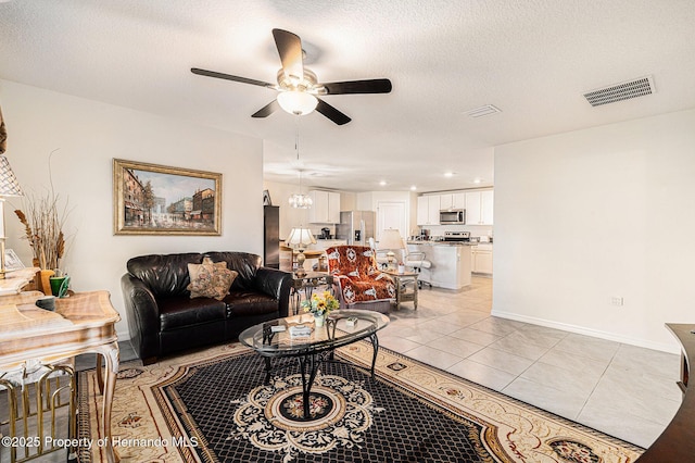 living area with light tile patterned floors, visible vents, a textured ceiling, and ceiling fan