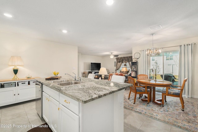 kitchen featuring dishwasher, light tile patterned floors, ceiling fan with notable chandelier, white cabinetry, and a sink