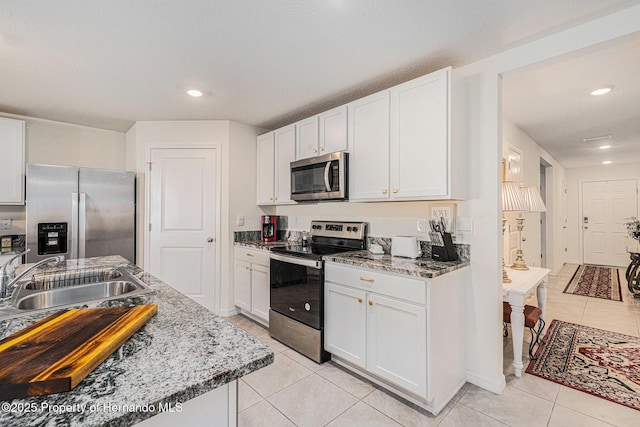 kitchen with white cabinets, light tile patterned floors, appliances with stainless steel finishes, and a sink