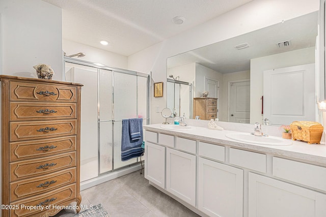 bathroom with tile patterned flooring, a shower stall, double vanity, and a sink