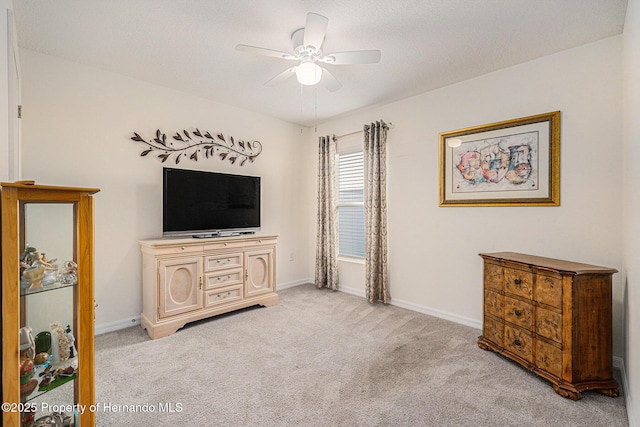 interior space with a ceiling fan, baseboards, and light carpet