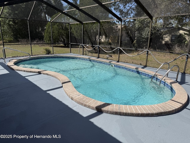 pool with glass enclosure and a patio area