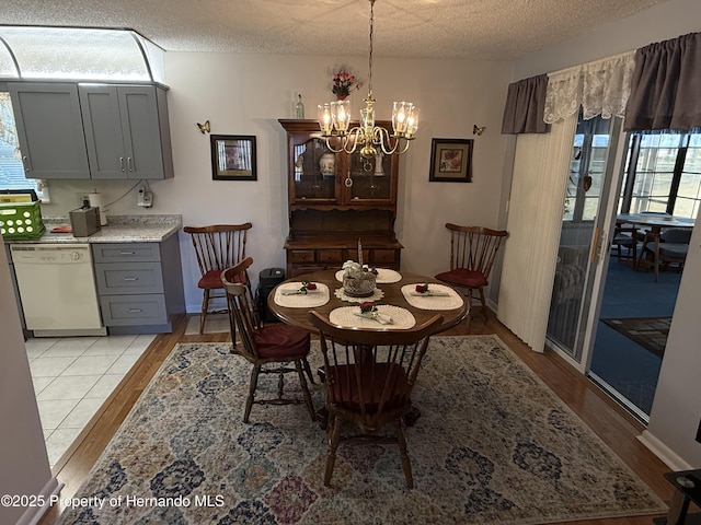 dining room with an inviting chandelier, light wood-style flooring, and a textured ceiling