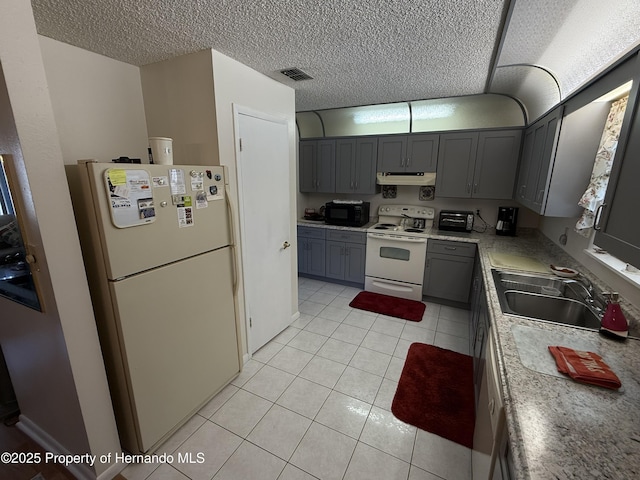 kitchen featuring visible vents, under cabinet range hood, light tile patterned floors, white appliances, and a sink