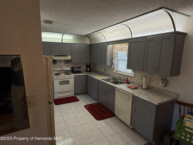 kitchen with visible vents, gray cabinets, white appliances, and a sink