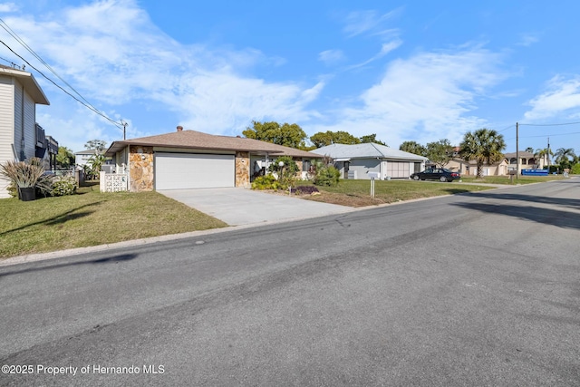 single story home with a front lawn, a residential view, concrete driveway, stone siding, and an attached garage