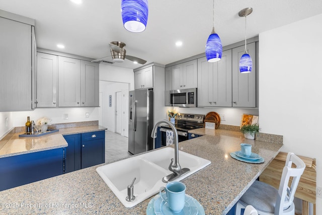 kitchen with recessed lighting, a sink, hanging light fixtures, stainless steel appliances, and a kitchen bar