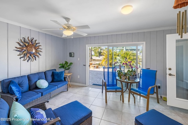 living room featuring light tile patterned floors, baseboards, a ceiling fan, and ornamental molding