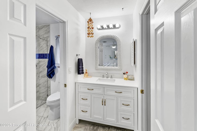 bathroom with tiled shower, marble finish floor, toilet, and vanity