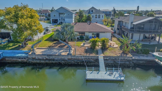 view of dock featuring a water view, a patio, a fenced backyard, a yard, and a residential view