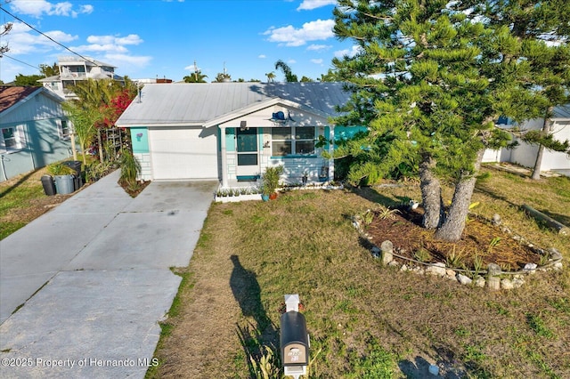 ranch-style home featuring a front lawn, a garage, driveway, and metal roof