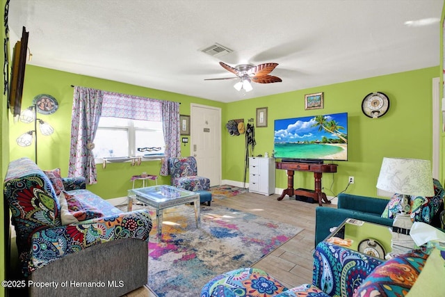 living room with visible vents, baseboards, ceiling fan, wood finished floors, and a textured ceiling