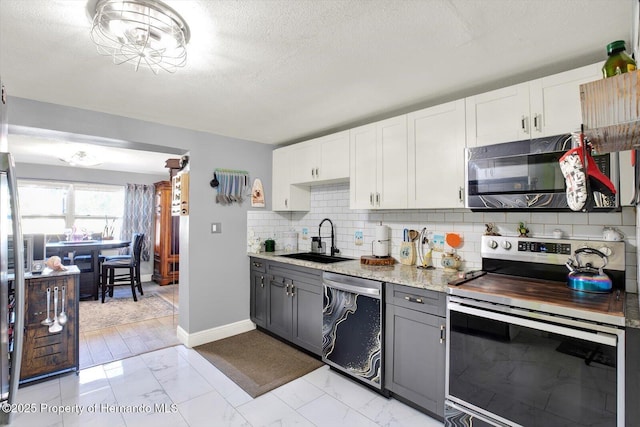 kitchen featuring a sink, backsplash, marble finish floor, and appliances with stainless steel finishes