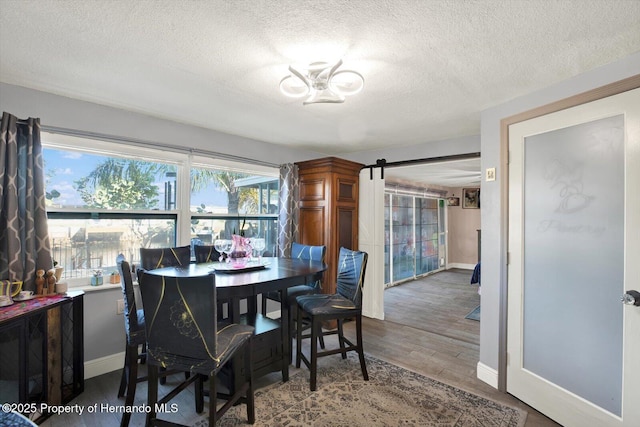 dining space featuring baseboards, a textured ceiling, and wood finished floors