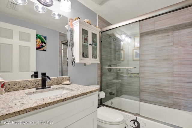 full bathroom featuring visible vents, toilet, vanity, and shower / bath combination with glass door