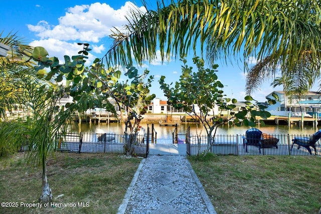 surrounding community with a yard, fence, a water view, and a boat dock