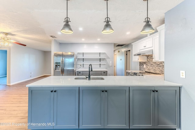 kitchen featuring a sink, light countertops, under cabinet range hood, and stainless steel appliances