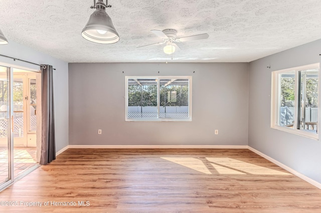 spare room featuring light wood-type flooring, baseboards, a textured ceiling, and a ceiling fan