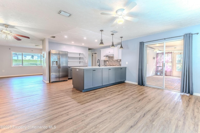 kitchen featuring backsplash, stainless steel fridge with ice dispenser, under cabinet range hood, a peninsula, and a ceiling fan