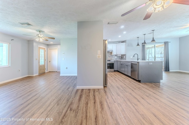 kitchen featuring visible vents, stainless steel appliances, ceiling fan, light countertops, and open floor plan