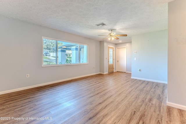 spare room with light wood finished floors, visible vents, baseboards, a textured ceiling, and a ceiling fan