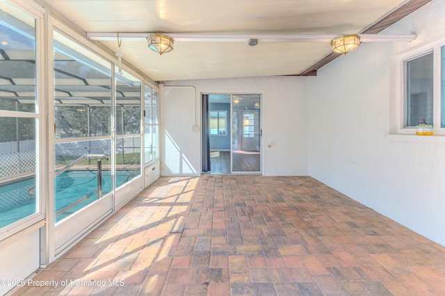 unfurnished sunroom featuring beam ceiling and a healthy amount of sunlight